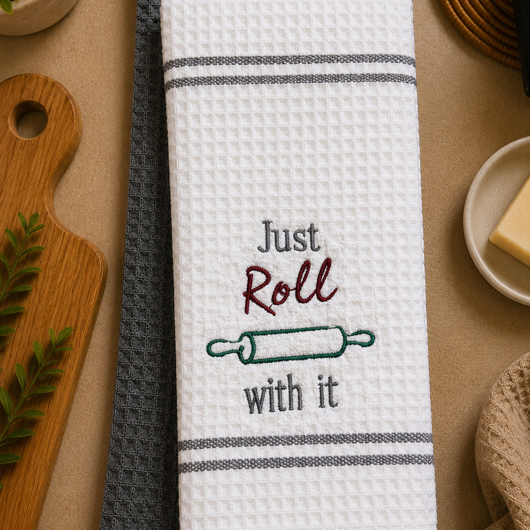 Embroidered kitchen towel set featuring "Just Roll With It" design by PressMark Studio, with colorful embroidered text and fabric towels.