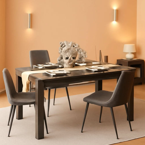 Grey wood dining table set with four chairs, placed on a light rug in a warmly colored room.