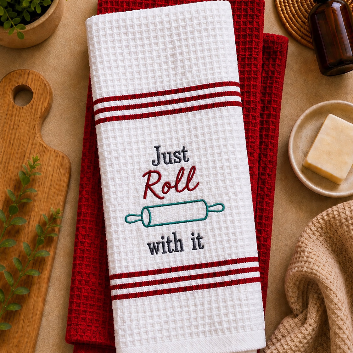 Set of embroidered kitchen towels with "Just Roll With It" design by PressMark Studio, soft cotton fabric in neutral tones.