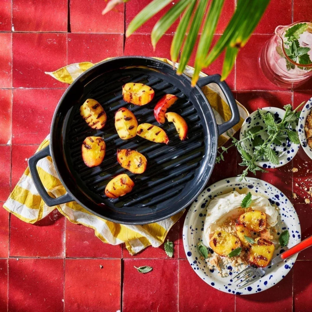 Alva Cookware 11-inch enameled cast iron grill pan with grilled vegetables on the surface, ideal for indoor grilling and searing.