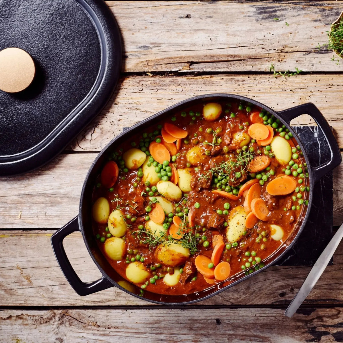 Enameled cast iron oval Dutch oven by Alva Cookware filled with vegetable stew, showing its shiny enamel and sturdy design.